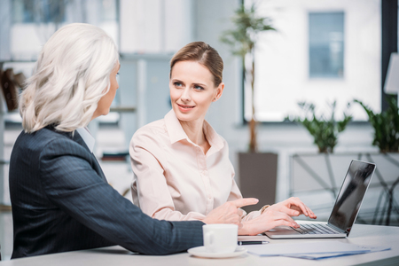 businesswomen talking while using laptop at workplaceの写真素材
