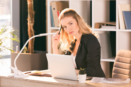 young businesswoman using laptop and looking at cameraの写真素材