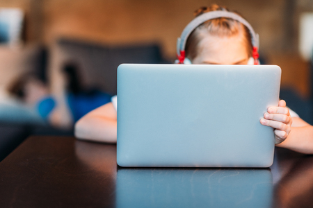 little girl in headphones using laptopの写真素材