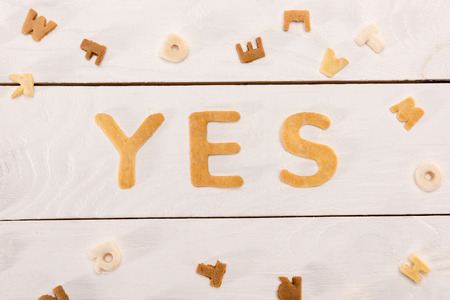 word yes from breakfast cereal letters and alphabet corn flakes on wooden tableの写真素材