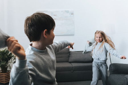 boy and girl playing pillow fight at homeの写真素材