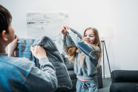 little children in pajamas having pillow fight at homeの写真素材