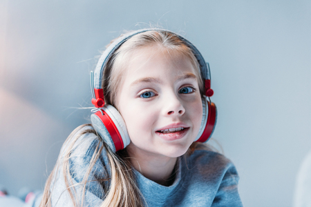 little girl listening music in headphones and looking at cameraの写真素材