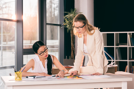 multiethnic businesswomen in formalwear talking at modern officeの写真素材