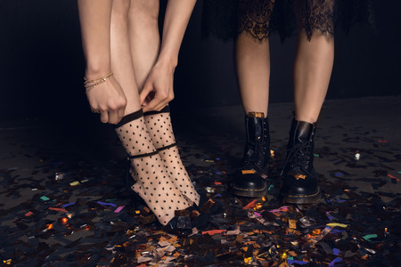 young women in stylish shoes standing on shiny confetti