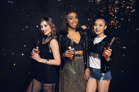 young women holding bottles of alcohol beverages and smiling at cameraの写真素材