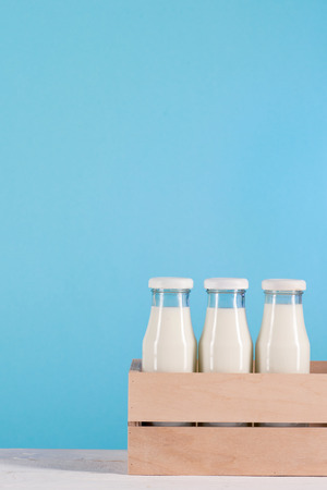 glass bottles with milk in wooden box on tabletopの写真素材