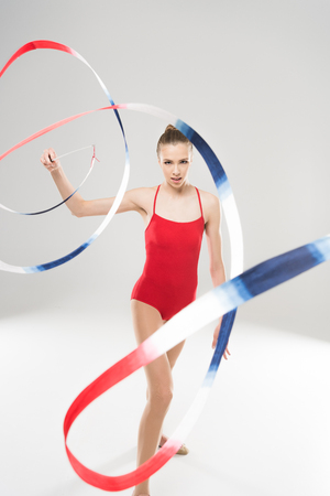young woman rhythmic gymnast exercising with colorful rope and looking at cameraの写真素材