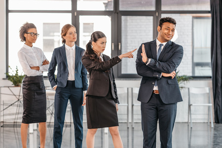 young emotional businesspeople in formalwear quarrelling at modern officeの写真素材