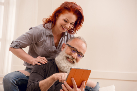 smiling senior man using digital tablet with wife near byの写真素材