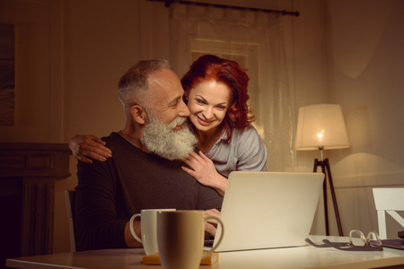 smiling middle aged couple looking at laptop at homeの写真素材