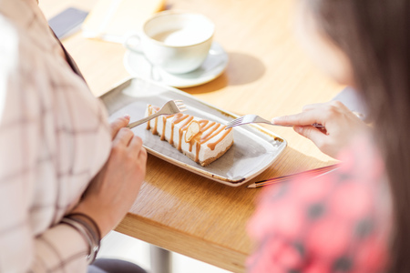 girls eating sweet dessert with forks at cafe, coffee break