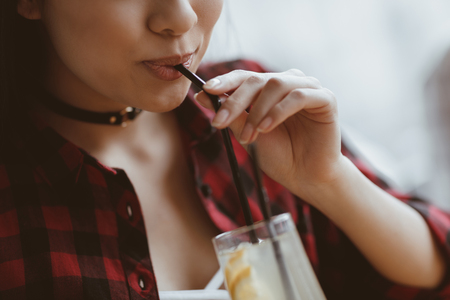 asian girl drinking latte with straw in cafe, having lunch conceptの写真素材
