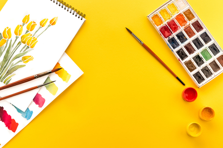 drawings of flowers, paints and brushes on yellow, springtime conceptの写真素材