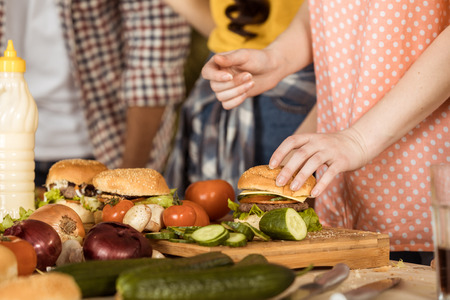 woman preparing hamburgers for friends on kitchen boardの写真素材