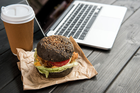 close up of burger with coffee to go and laptopの写真素材