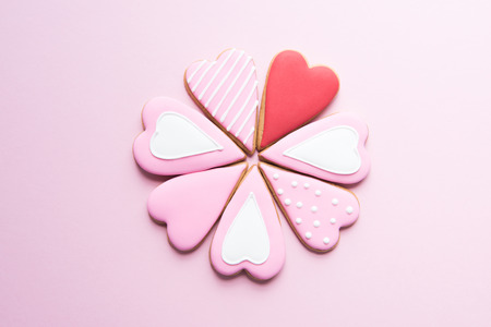 Above view of handmade cookies with colorful icing in heart shape on pink surface