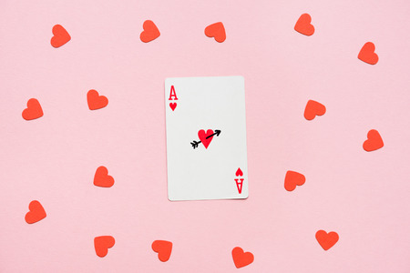Heart ace of playing card with red hearts lying around on pink surfaceの写真素材