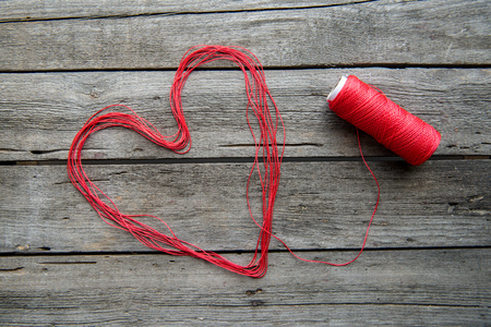 Heart sign made from red thread on wooden surfaceの写真素材