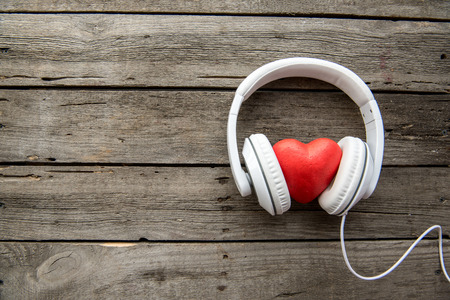 White headphones with red heart sign in the middle on wooden backgroundの写真素材