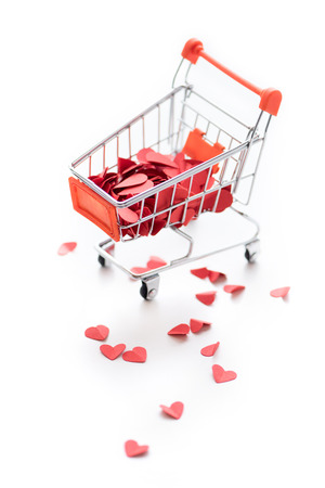 Full shopping trolley of red hearts isolated on whiteの写真素材