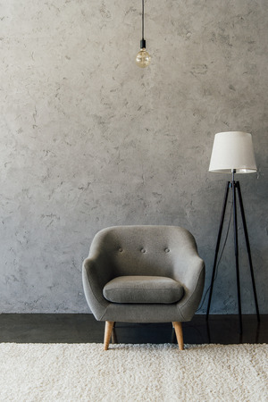 Cozy grey armchair on white carpet and modern lamp in empty roomの写真素材
