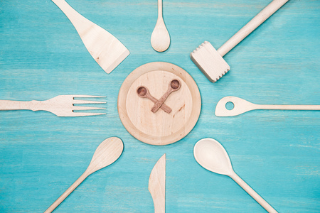 top view of various wooden kitchen utensils with clock symbol on plateの写真素材