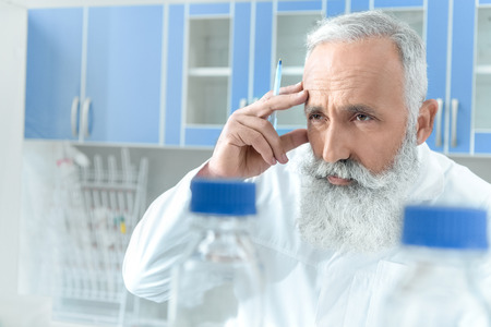senior bearded chemist in white coat in chemical laboratoryの写真素材