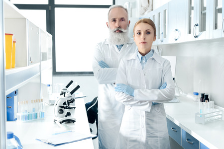 confident scientists in white coats looking at camera and posingの写真素材