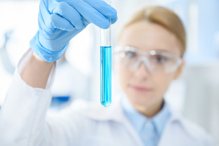 professional scientist holding test tube with reagent in lab