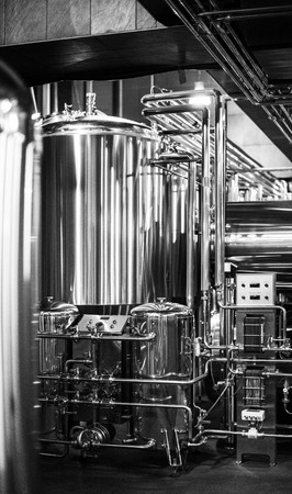 Black and white photo of modern brewery equipment with pipes and fermenting tankの写真素材
