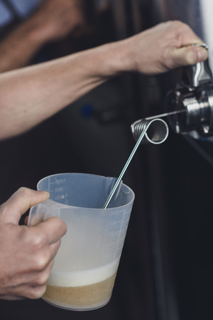 Hands of  brewery worker pouring beer from the tank to plastik pitcherの写真素材