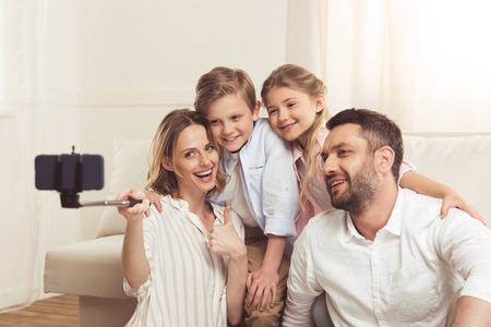 family taking selfie on smartphone with monopod at home
