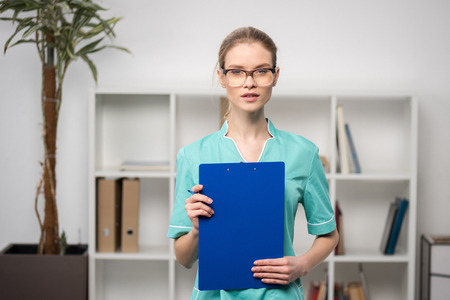 confident doctor with clipboard looking at camera at hospitalの写真素材