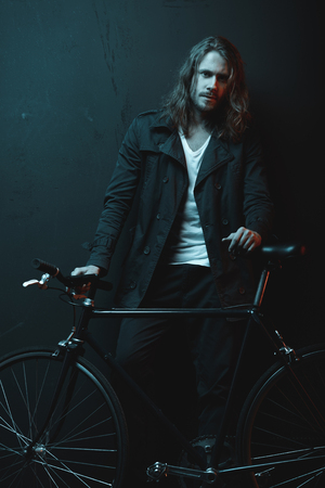 young bearded man standing with hipster bicycle and looking at camera young bearded man standing with hipster bicycle and looking at camera