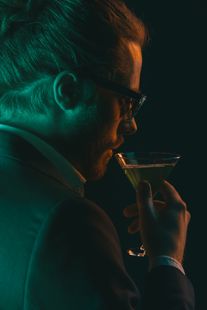 young elegant man drinking cocktail from glassの写真素材
