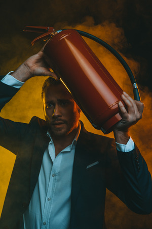 caucasian man in suit holding fire extinguisherの写真素材