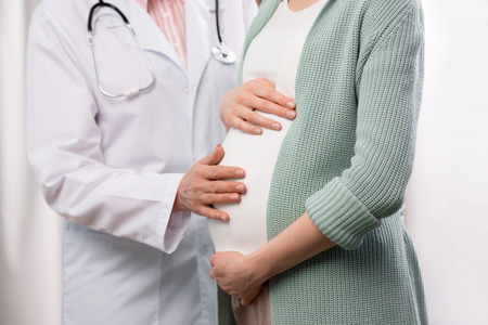 doctor examining pregnant woman during medical consultationの写真素材