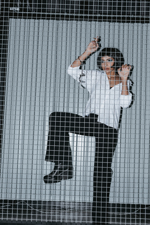 woman in white shirt with cuffs standing behind grateの写真素材