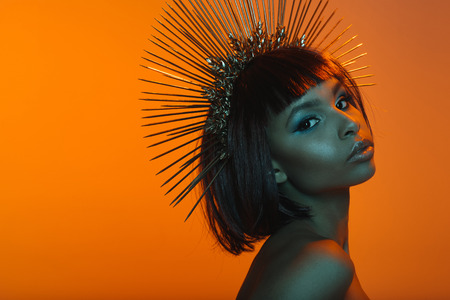 african american girl in headpiece with needles looking at cameraの写真素材
