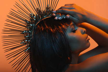 fashionable african american woman in headpiece with hands on headの写真素材