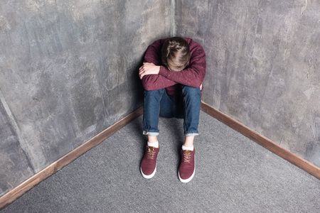 depressed teenage boy sitting on floorの写真素材