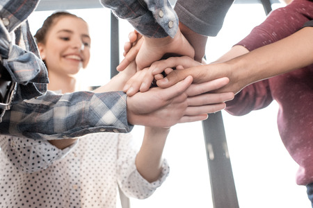 teenagers stacking hands together indoors, teenagers having fun concept