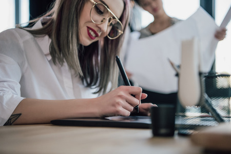 young businesswoman in eyeglasses using graphic tablet in officeの写真素材