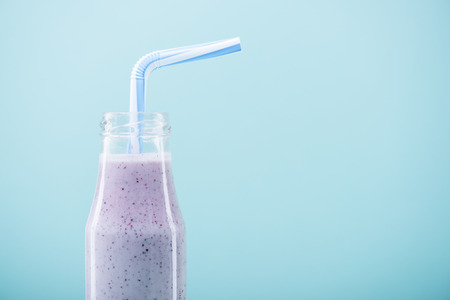 delicious fruity milkshake in glass bottle with drinking strawの写真素材