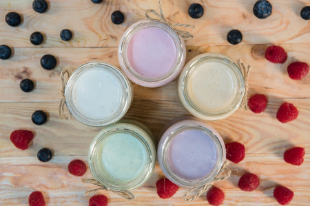 jars with berry milkshakes and berries on wooden tabletopの写真素材