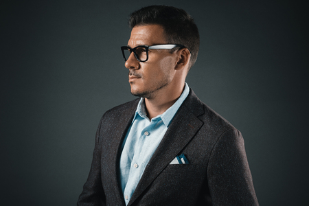 confident stylish man in eyeglasses looking away isolated on greyの写真素材