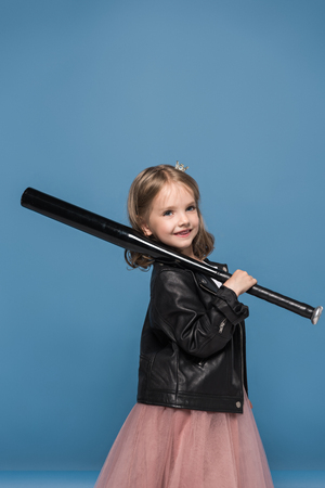 little girl in leather jacket smiling and holding baseball batの写真素材