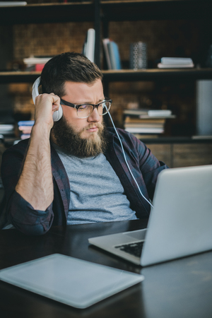 serious businessman in headphones working at home officeの写真素材