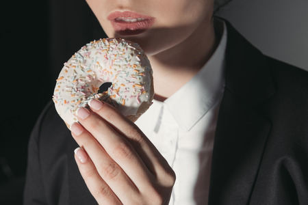 woman eating sweet glazed donutの写真素材